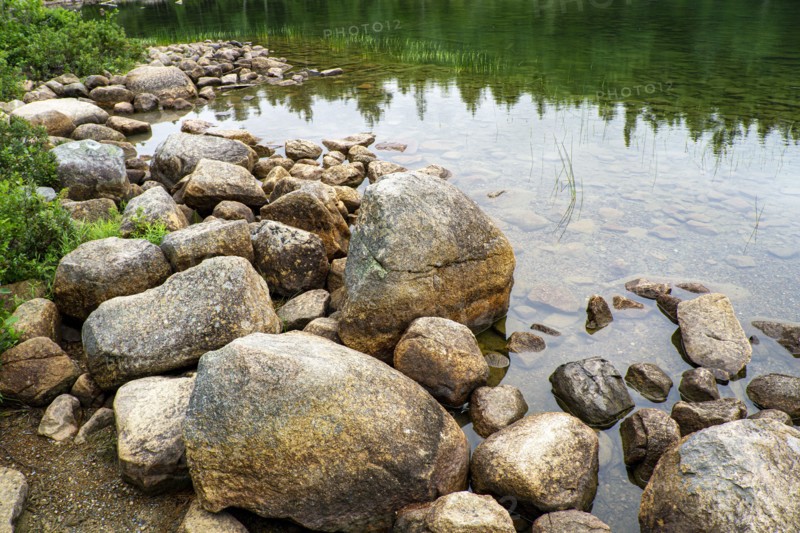 Large rocks at edge of clear lake, Acadia National Park, Maine, USA