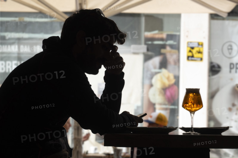 Silhouette of mid-adult man looking at his smartphone at café