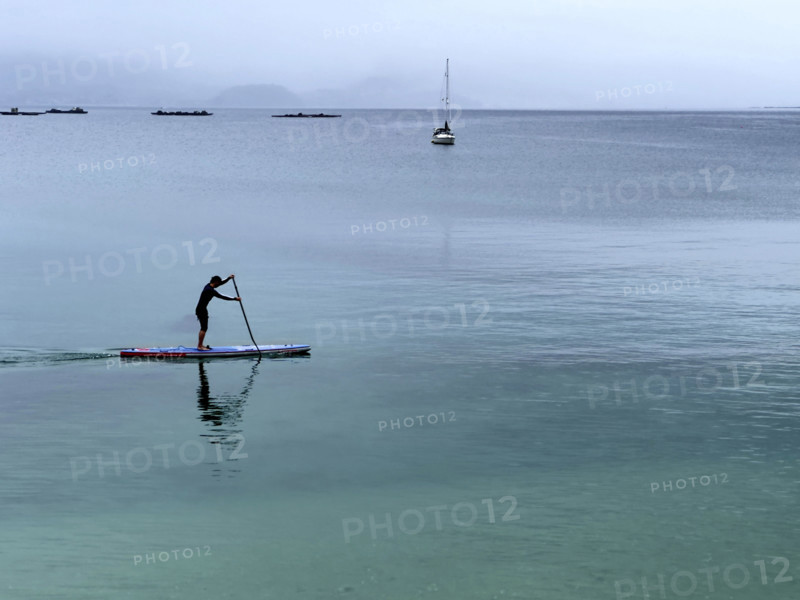 Man paddle boarding on calm water, Bueu, Pontevedra, Galicia, Spain