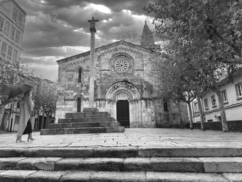 Woman with umbrella walking towards old church, A Caruña, Galicia, Spain