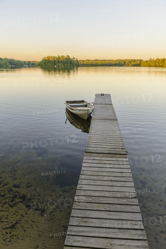 Row boat moored at dock on scenic lake at sunset