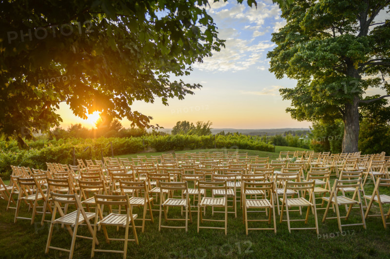 Rows of wood folding chairs set up for outdoor event at sunset