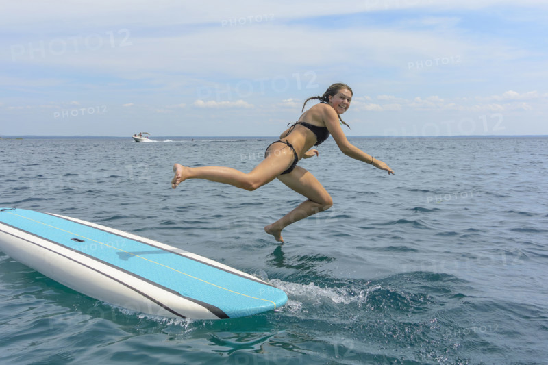 Young adult woman jumping off paddle board