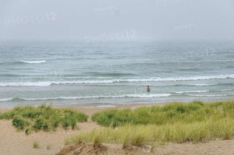 Rear view of swimmer wading into lake on cloudy day