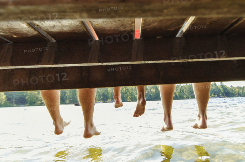 Family with dangling feet sitting on dock