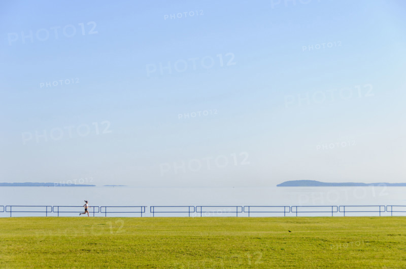 Young adult woman running along lake