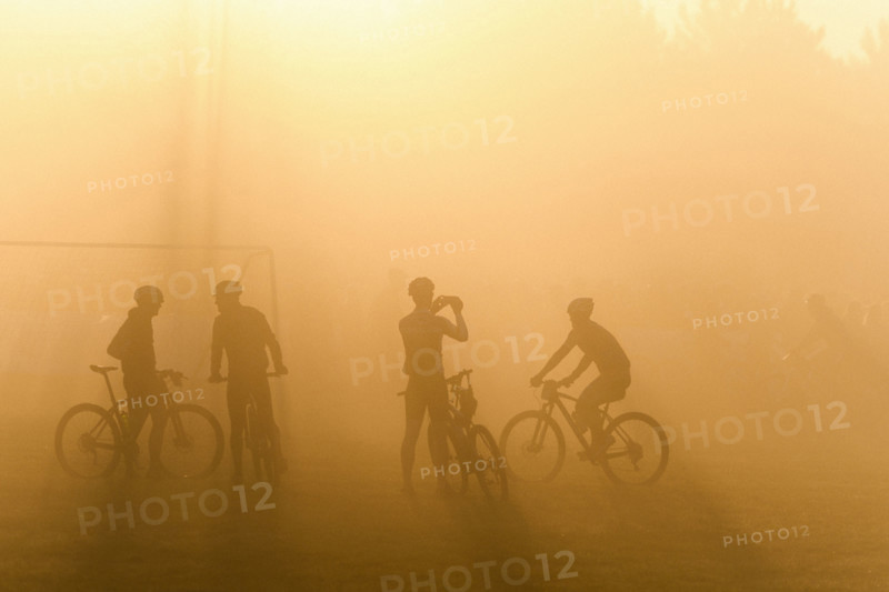 Silhouette of four cyclists waiting in fog for start of bike race