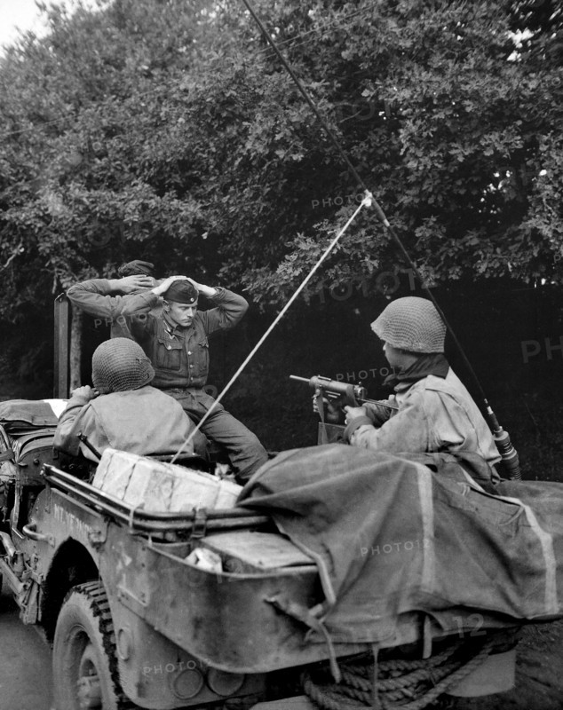 Two German prisoners of war being taken to U.S. 6th Division Prisoner of War Encampment for interrogation and searching, Plouay, France, U.S. Army Signal Corps, August 28, 1944