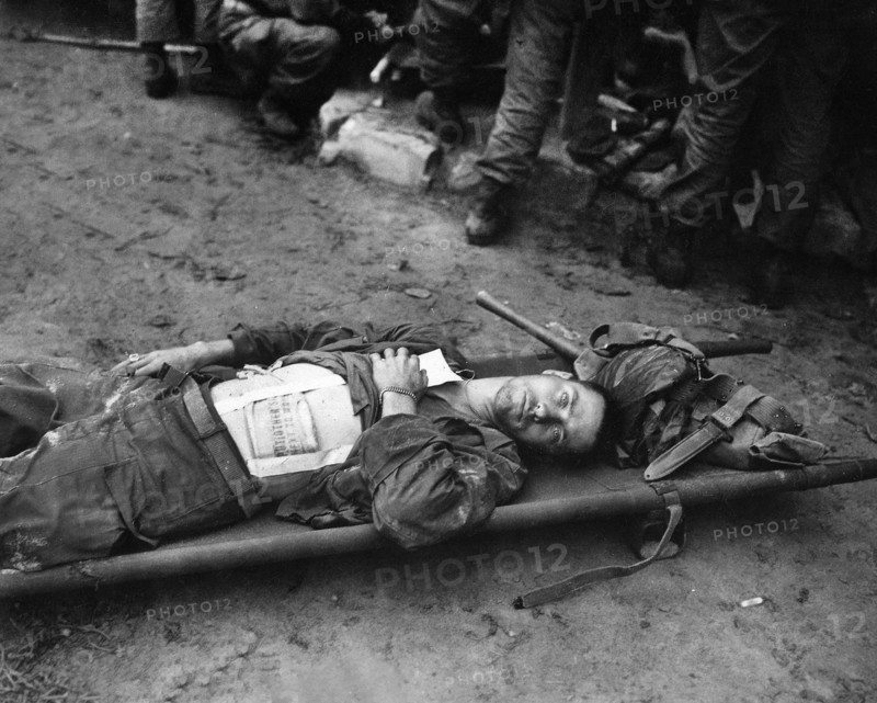 Private First Class, Thomas Conlon, 21st Infantry Regiment, laying on stretcher at medical aid station, after being wounded while crossing the Nakdong River, South Korea, U.S. Army Signal Corps, September 19, 1950