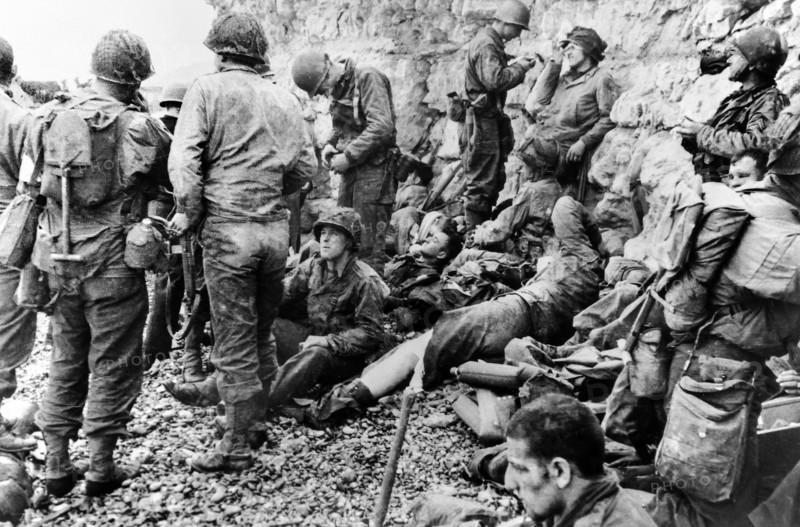 American assault troops of the 3rd Battalion, 16th Regiment, 1st US Infantry Division, gained comparative safety offered by chalk cliffs, resting before moving inland, Omaha Beach, Colleville-sur-Mer, Normandy, France, U.S. Army Signal Corps, June 6, 1944