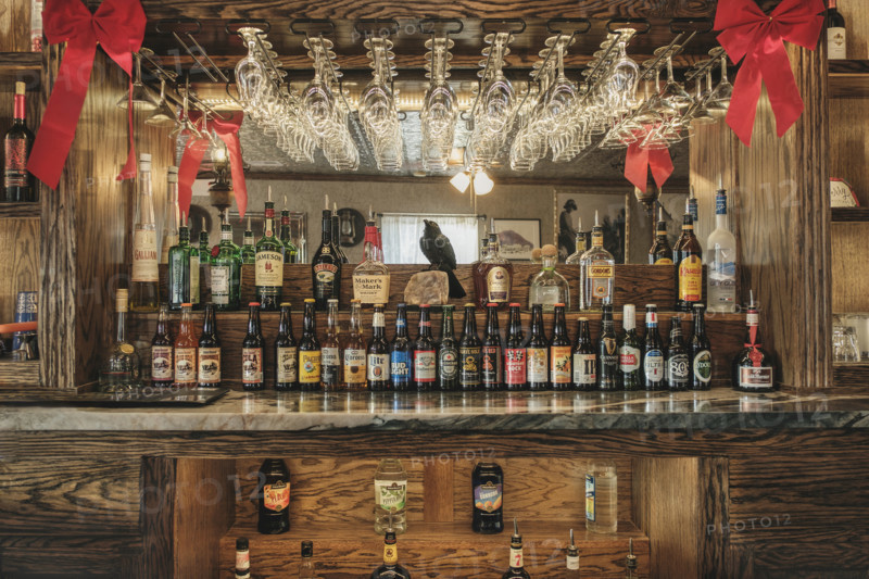 Saloon interior with rows of liquor and beer bottles on bar counter