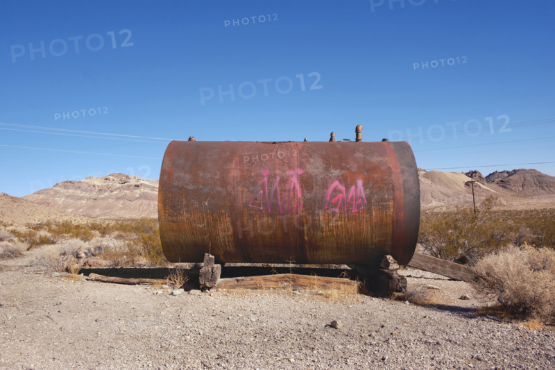 Rusted metal storage tank with painted graffiti in abandoned ghost town, Rhyolite, Nevada, USA