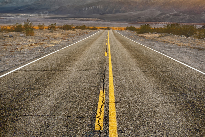 Two-lane asphalt road with mountains in background, diminishing perspective, Death Valley National Park, California, USA