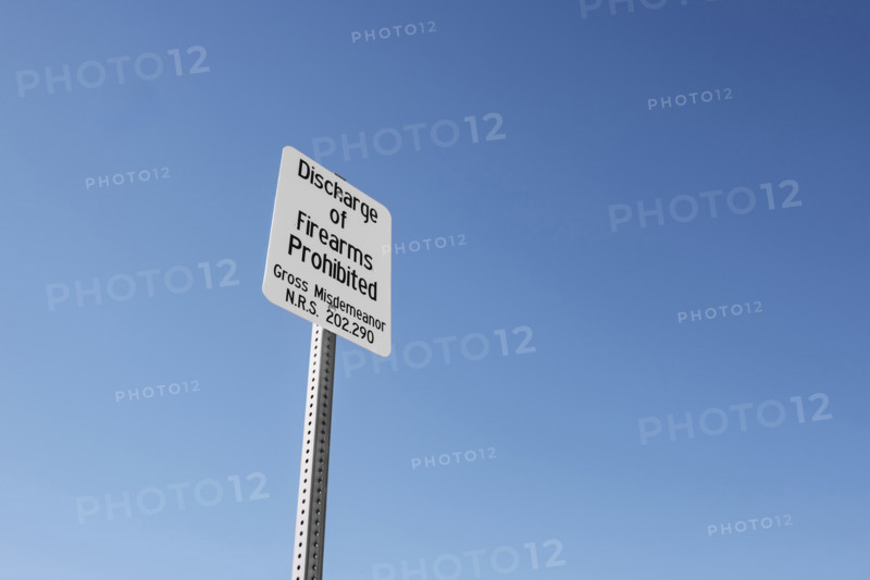 Discharge of Firearms Prohibited' warning sign, low angle view against blue skey,