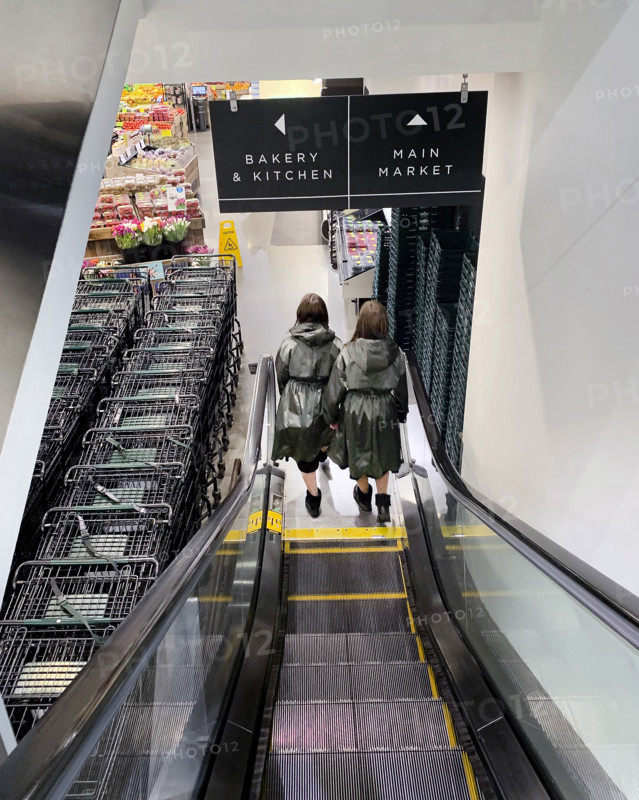 Rear view of two women descending escalator at supermarket, Brooklyn, New York, USA