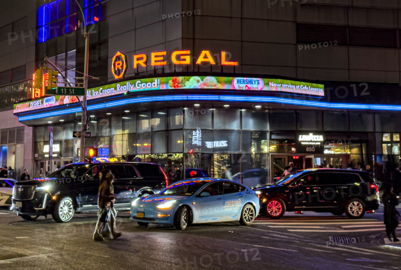 Regal movie theaters and street scene at night, New York City, New York, USA