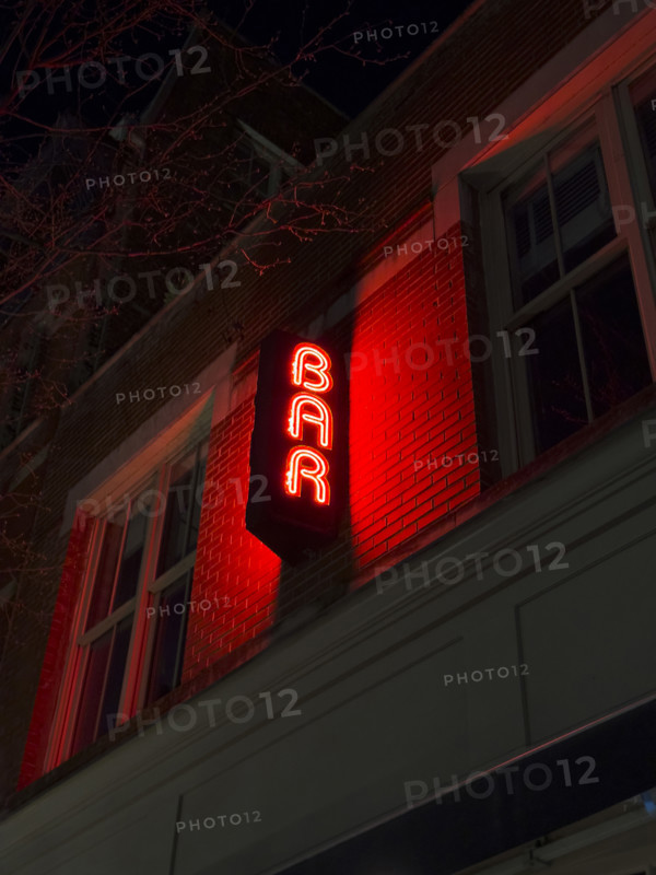 Neon red bar sign on building exterior at night, New York City, New York, USA
