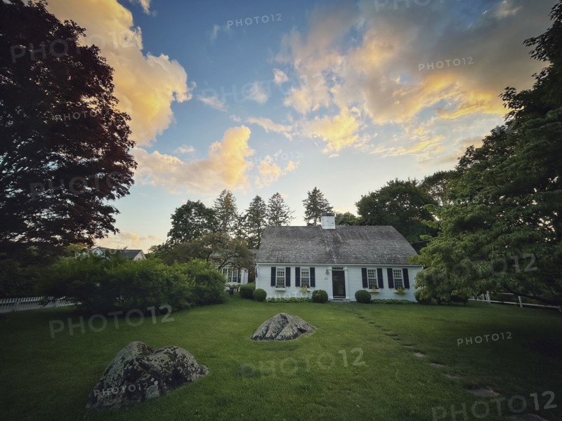 Bow roof cape house and front yard against sunset sky