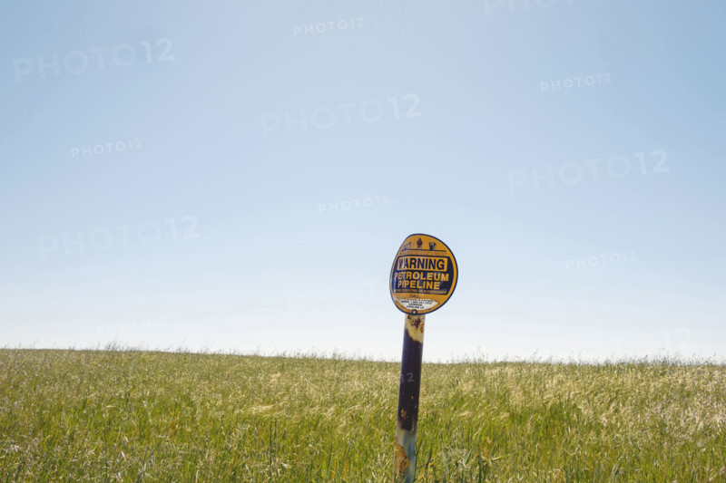 Buried petroleum pipeline warning sign in rural field
