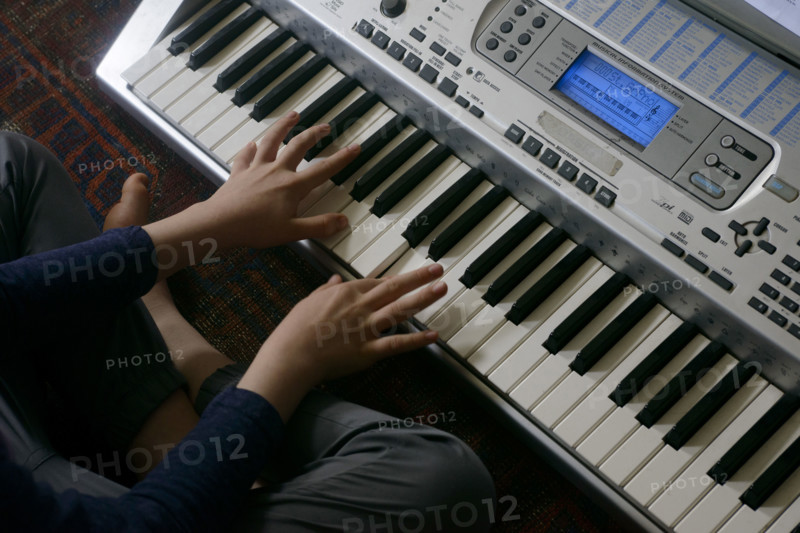 High angle view of young boy playing electric keyboard