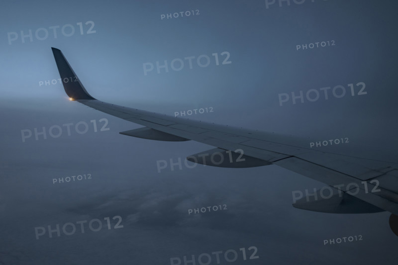 Commercial airplane wing viewed from passenger window at dusk