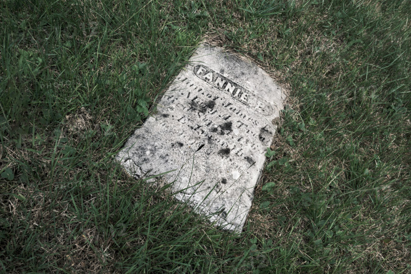 Old weathered gravestone laying on grass field