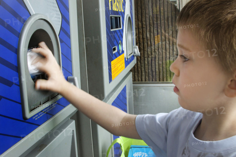 Young boy recycling cans in recycling bin