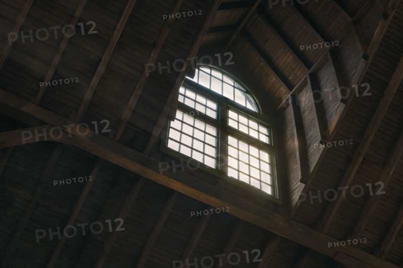 Low angle view of daylight coming through arched window in old wood-framed building