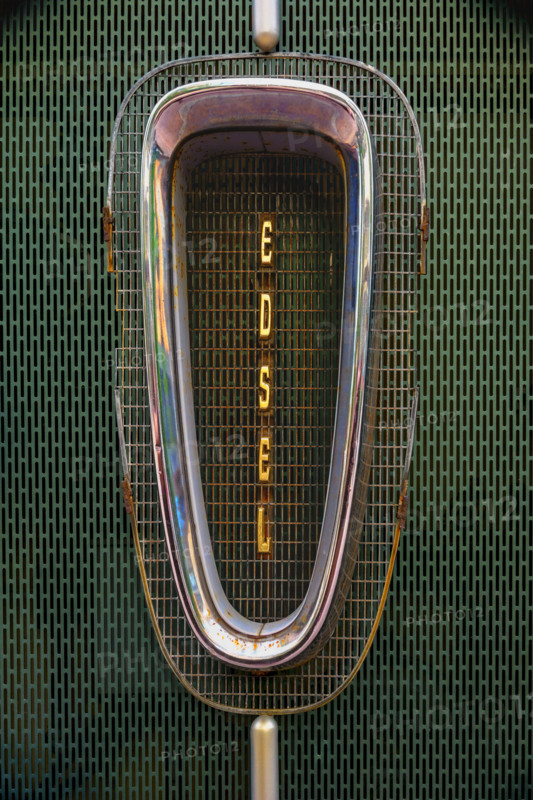 Antique rusted Ford Edsel car grille against green metal background