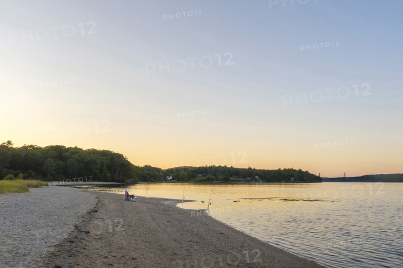 Two people fishing at beach at sunset