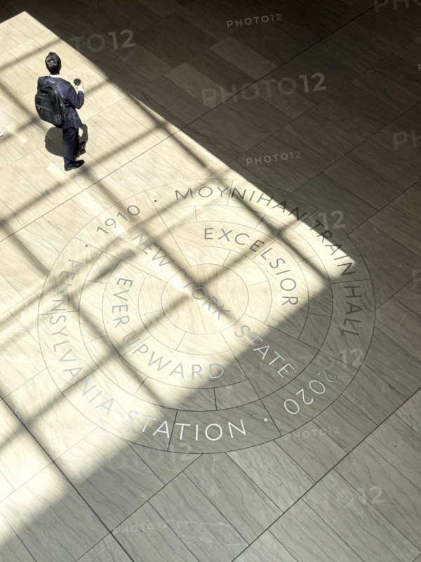 High angle view of commuter walking across New York State motto engraved on floor of Moynihan Train Hall, Pennsylvania Station, Manhattan, New York City, New York, USA