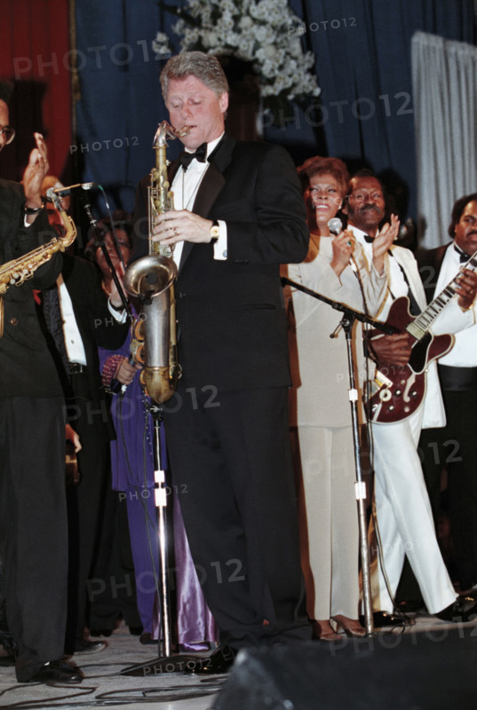 U.S. President Bill Clinton playing saxophone, as singer Dionne Warwick and others look on, at one of his inauguration balls, Arkansas Inaugural Ball, Washington Convention Center, Washington, D.C., USA, Bob McNeely, White House Photographer, January 20, 1993