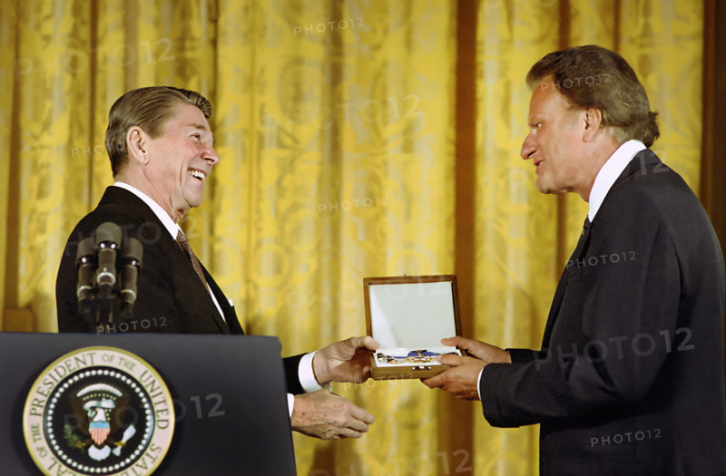 U.S. President Ronald Reagan presenting American evangelist Billy Graham in the East Room of the White House, Washington, D.C., USA, President Ronald Reagan White House Photographic Office, February 23, 1983