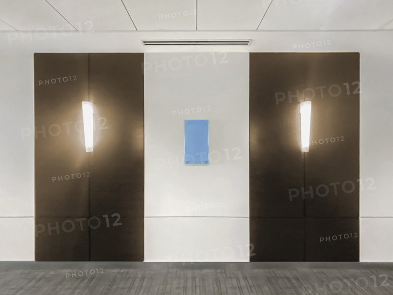 Two light fixtures mounted on hallway wall in office building