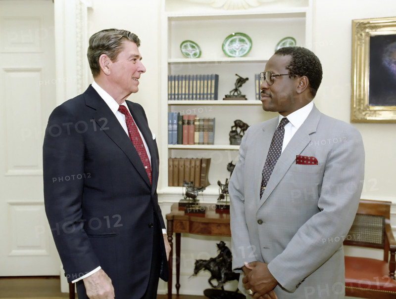U.S. President Ronald Reagan in the White House Oval Office during farewell photo opportunity with Clarence Thomas of The Equal Employment Opportunity Commission, Washington, D.C., USA, President Ronald Reagan White House Photographic Office, June 23, 1986