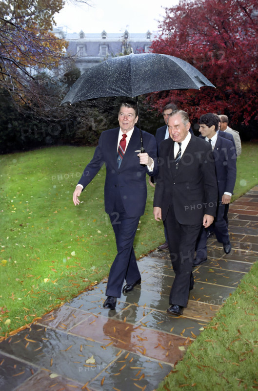 U.S. President Ronald Reagan holding umbrella while walking with President Chaim Herzog of Israel outside of White House Oval Office, Washington, D.C., USA, President Ronald Reagan White House Photographic Office, November 10, 1987
