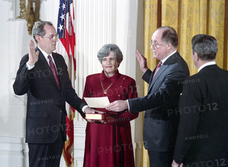 U.S. President Ronald Reagan watching swearing-in ceremony for Judge Anthony Kennedy as associate justice of The United States Supreme Court By Chief Justice William Rehnquist with Mary Kennedy holding bible, White House East Room, Washington, D.C., USA, President Ronald Reagan White House Photographic Office, February 18, 1988