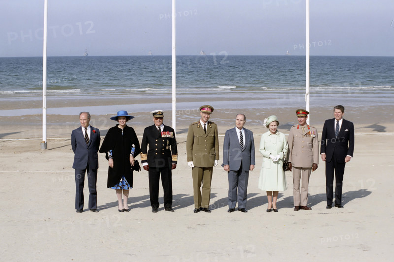 Canada Prime Minister Pierre Trudeau, Queen Beatrix of the Netherlands, King Olav V of Denmark, King Baudouin I of Belgium, President of France Francois Mitterrand, Queen Elizabeth II of Great Britain, Grand Duke Jean of Luxembourg and U.S. President Ronald Reagan attending 40th Anniversary of D-Day landings ceremony, Omaha Beach, Colleville-sur-Mer, France, President Ronald Reagan White House Photographic Office, June 6, 1984
