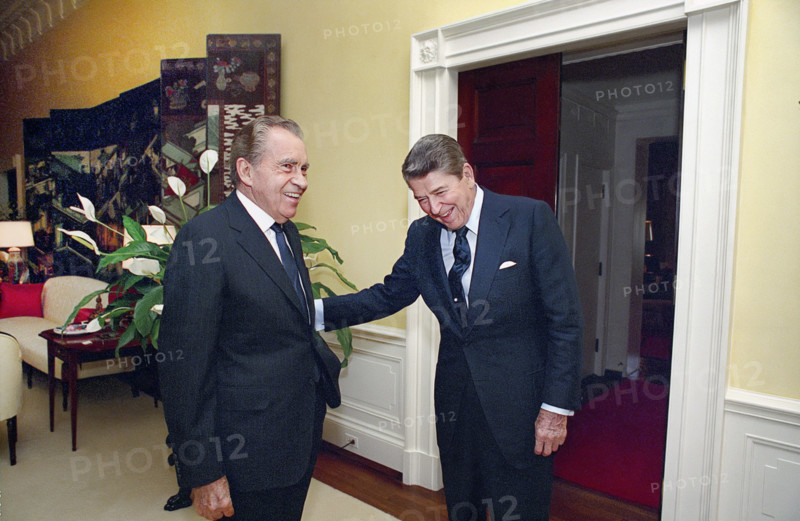 U.S. President Ronald Reagan laughing with former U.S. President Richard Nixon in White House center hall private residence, Washington, D.C., USA, President Ronald Reagan White House Photographic Office, July 28, 1988