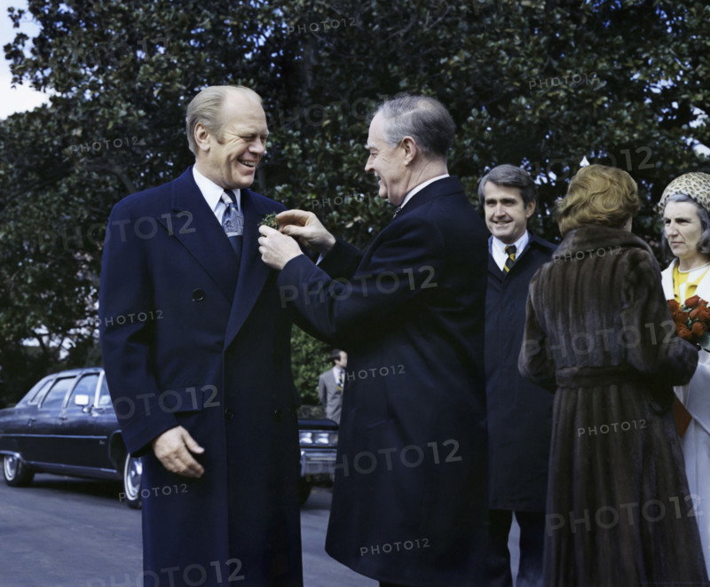 Prime Minister Liam Cosgrave of Ireland pinning shamrocks on U.S. President Gerald R. Ford's lapel in the White House South Driveway upon his arrival for a state visit, U.S. First Lady Betty Ford greeting Vera Cosgrove on right, Washington, D.C., USA, Gerald R. Ford White House Photographs, March 17, 1976