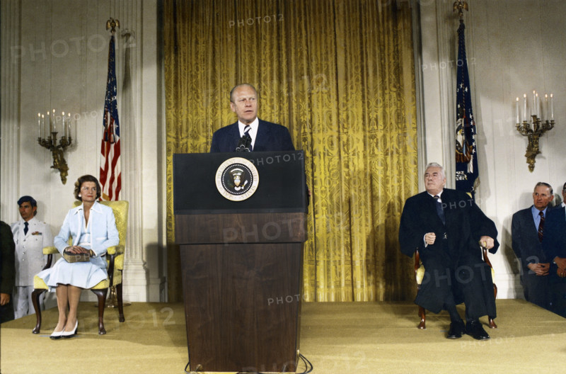 U.S. President Gerald R. Ford delivering remarks upon being sworn in as 38th President of the United States, U.S. First Lady Betty Ford sitting left, U.S. Supreme Court Chief Justice Warren Burger sitting right, White House East Room, Washington, D.C., USA, Gerald R. Ford White House Photographs, August 9, 1974