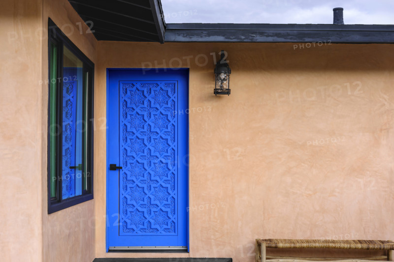 Blue carved wood door on stucco house