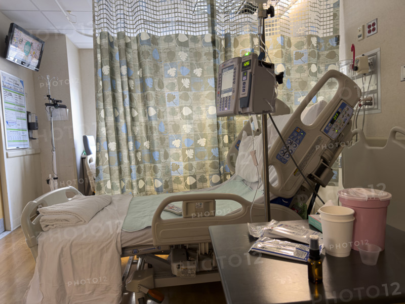 Empty hospital bed in patient room with medical equipment