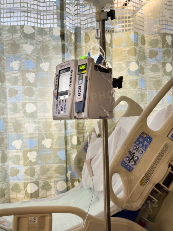 Empty hospital bed in patient room with medical equipment