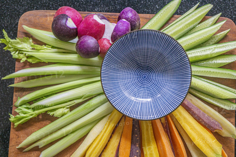 High angle view of fresh cut vegetables with blue bowl on wood board