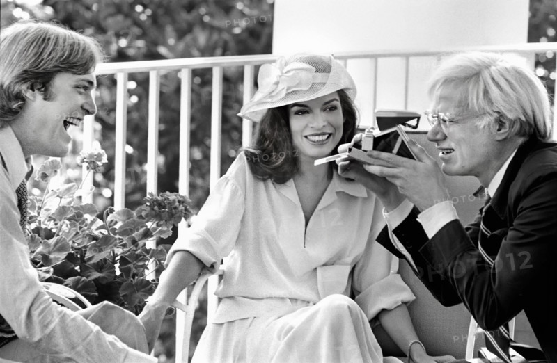 American artist Andy Warhol taking Polaroid picture while sitting with Jack Ford and Bianca Jagger on White House Truman Balcony, Washington, D.C., USA, Gerald R. Ford White House Photographs, July 2, 1975