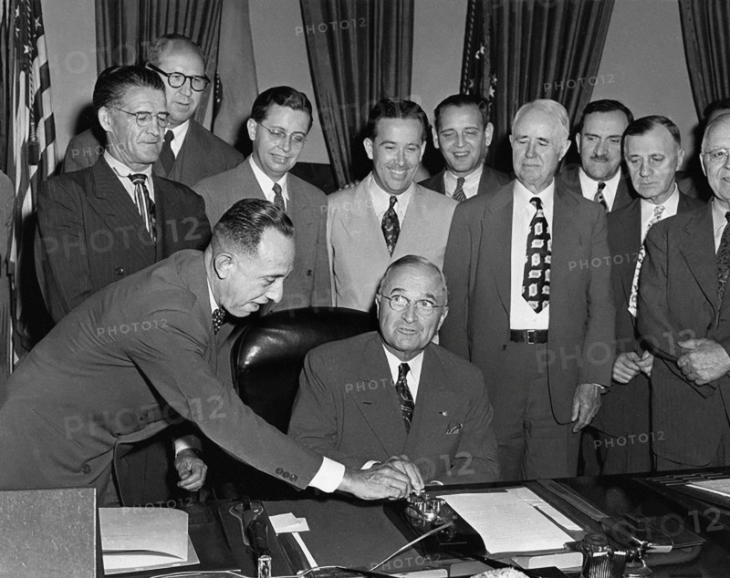 U.S. President Harry S. Truman seated at his desk preparing to push button activating a new generator at Grand Coulee Dam, as unidentified members of Congress from a number of Western states look on, White House Oval Office, Washington, D.C., USA, Abbie Rowe, National Parks Service, Harry S. Truman Library, May 20, 1949