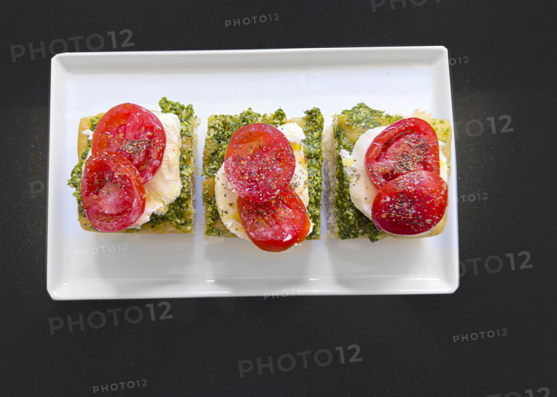 Tomato, mozzarella, basil and pesto and toasted bread on white plate