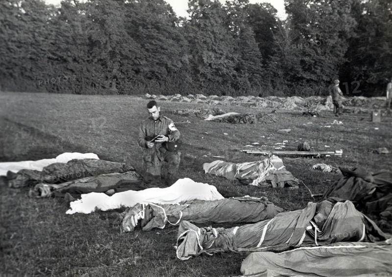 U.S. Army Chaplain Francis L. Sampson of Sioux Falls, S.D., giving absolution to American paratroopers killed in action, Saint Marie Dumont, France, Runyan, U.S. Army Signal Corps, June 7, 1944