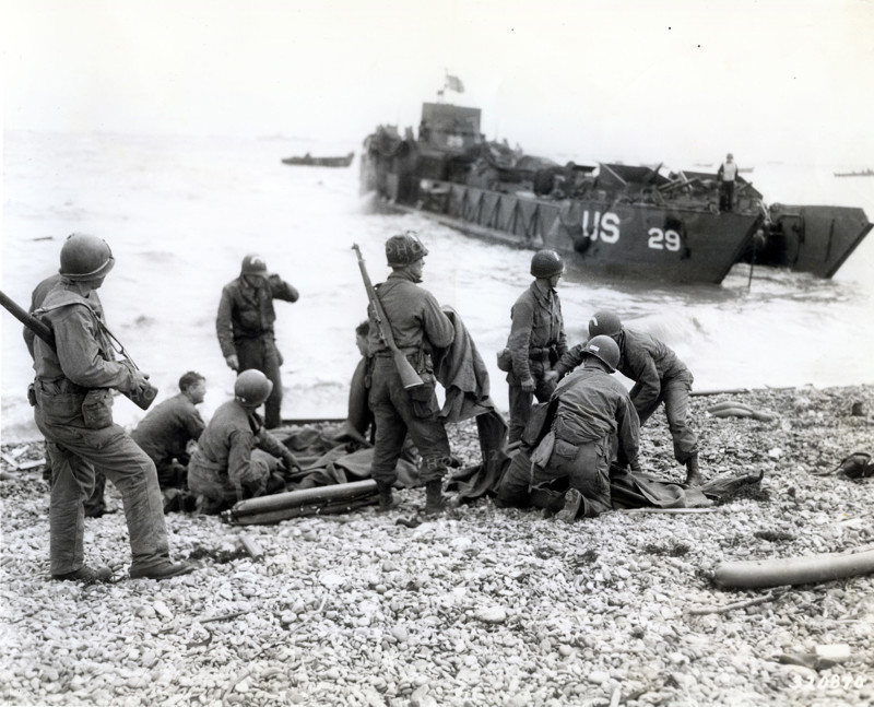 American soldiers applying artificial respiration on two other soldiers who reached the north coast of France in rubber life raft after their landing craft was sunk by enemy action while several hundred yards from shore, near Cherbourg, Normandy, France, Weintraub, U.S. Army Signal Corps, June 6, 1944